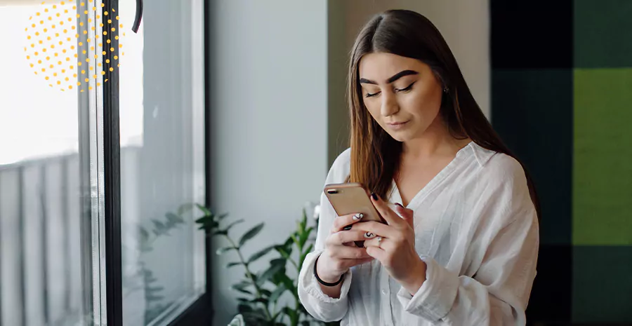 imagem de uma mulher perto de uma janela mexendo no celular, representando a Portaria 373