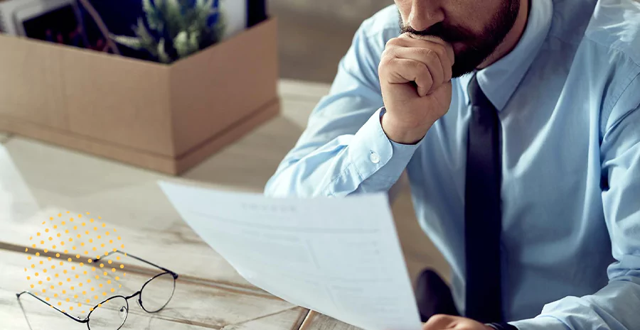 imagem de um homem segurando um papel com um óculos em cima da mesa