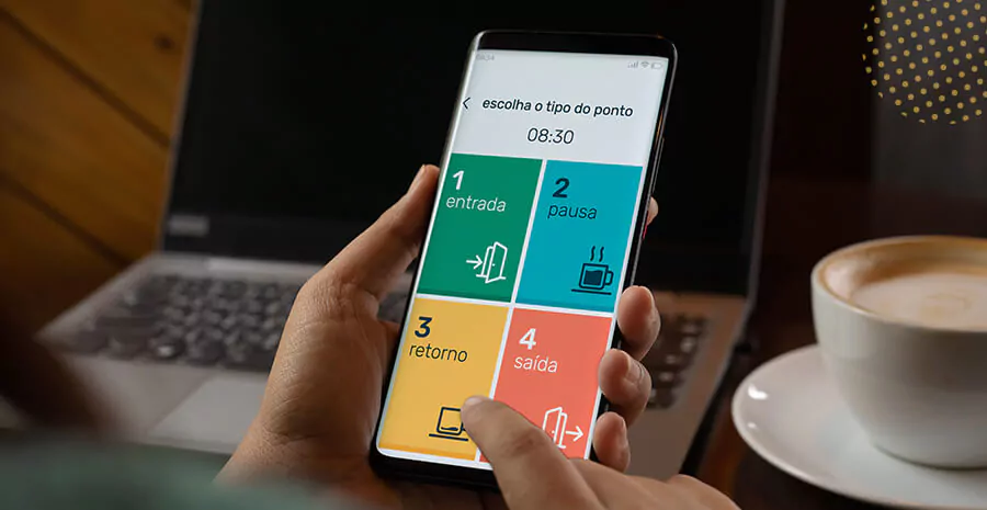 imagem do aplicativo de ponto da pontotel num celular e uma pessoa segurando o celular com um notebook ao fundo