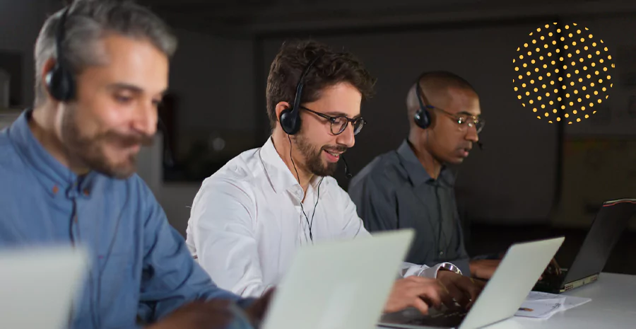 Três homens de fones utilizando computadores