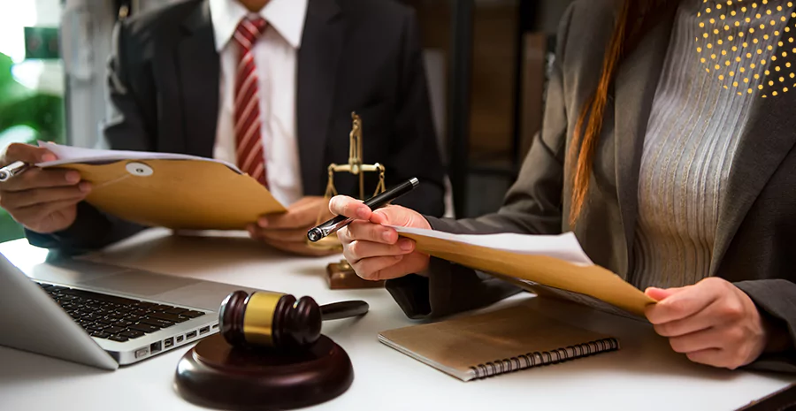 Um homem e uma mulher de roupa social segurando papeis