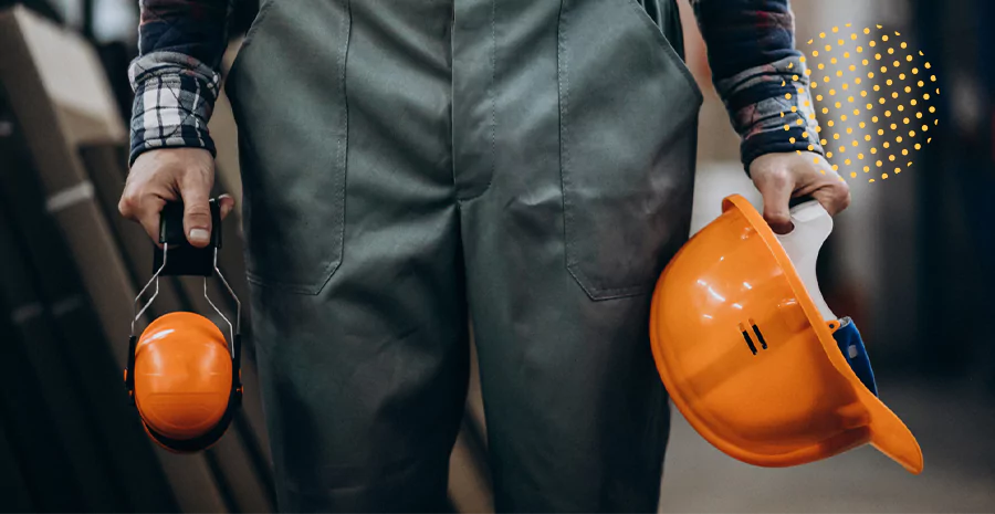 Homem segurando um capacete e fone usado em construção