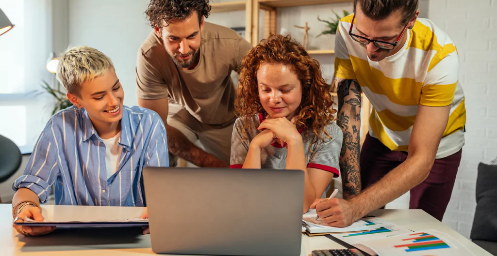 grupo de pessoas reunidas em volta de um notebook
