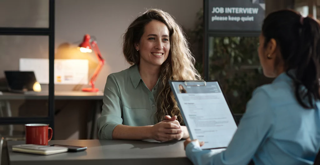 Uma mulher está conversando com outra mulher em uma entrevista de emprego