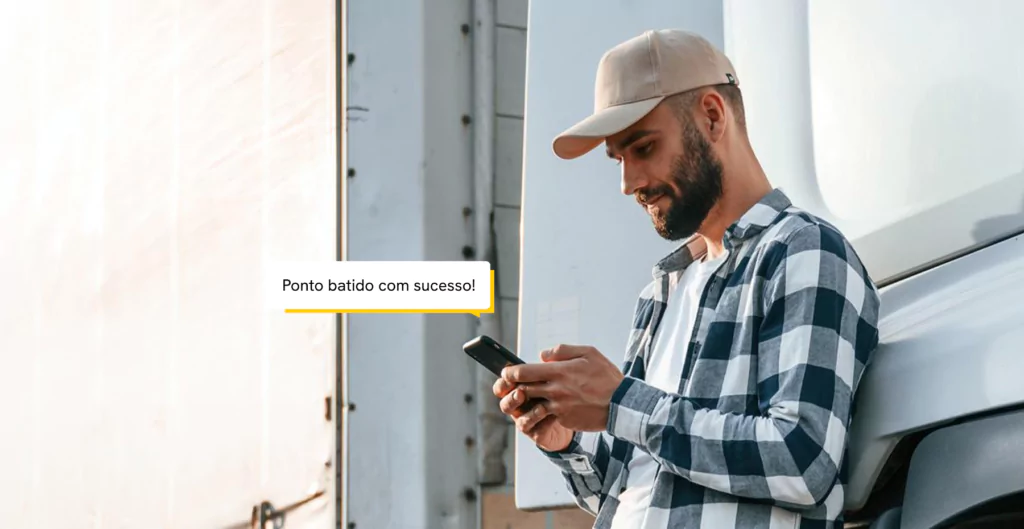 Trabalhador confirmando registro de ponto pelo celular ao lado de um caminhão.