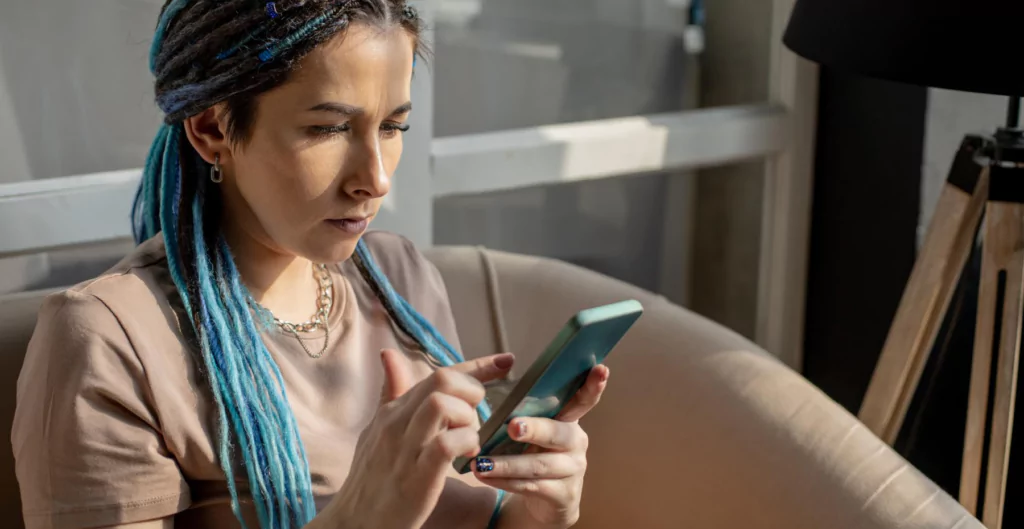 Mulher usando celular com expressão séria, ilustrando tentativa de registrar ponto remotamente.