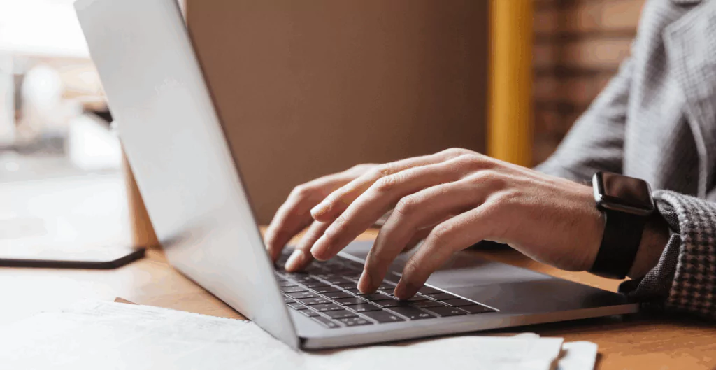 Homem digitando no notebook os termos do acordo com o sindicato para trabalhar aos domingos e feriados, formalizando a nova jornada.