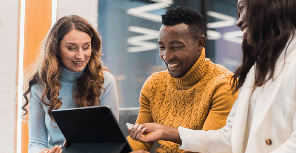 Grupo de pessoas sorrindo durante uma consulta médica, com uma mulher entregando uma ficha ou receita, todos felizes e alegres na conversa.